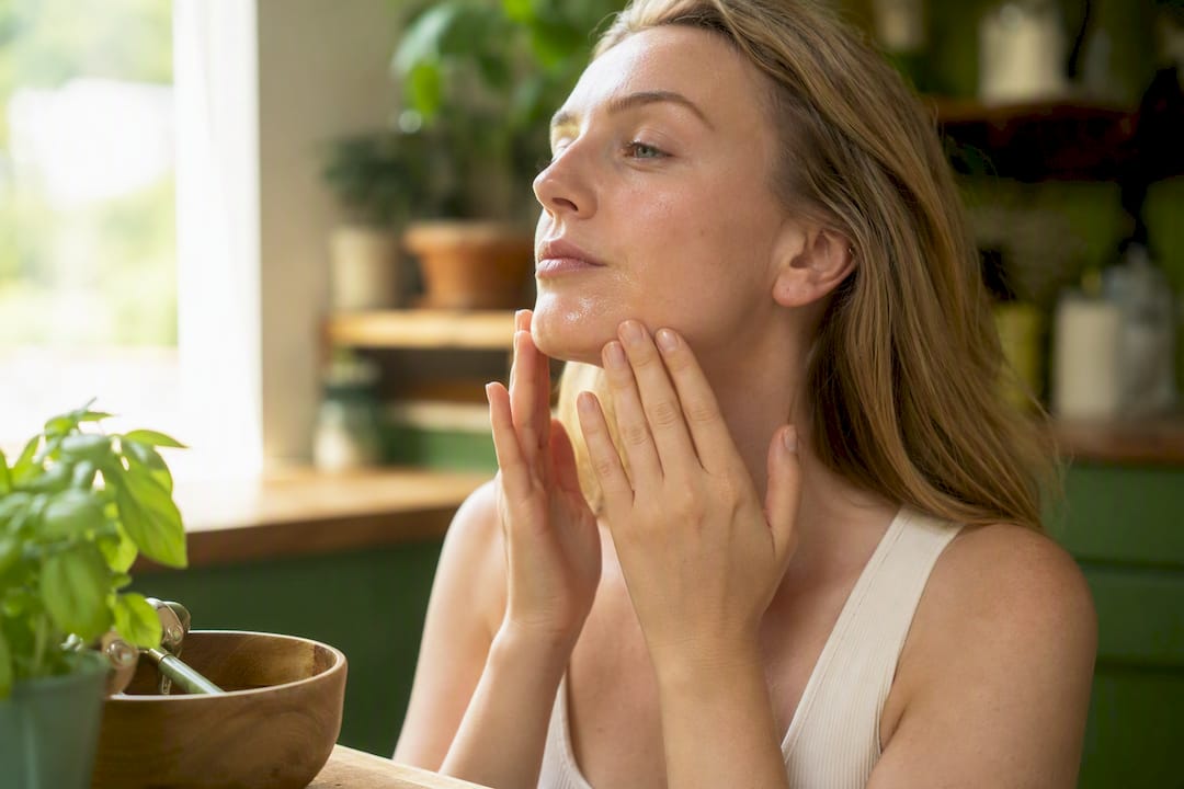 Close-up of hand applying serum near jawline