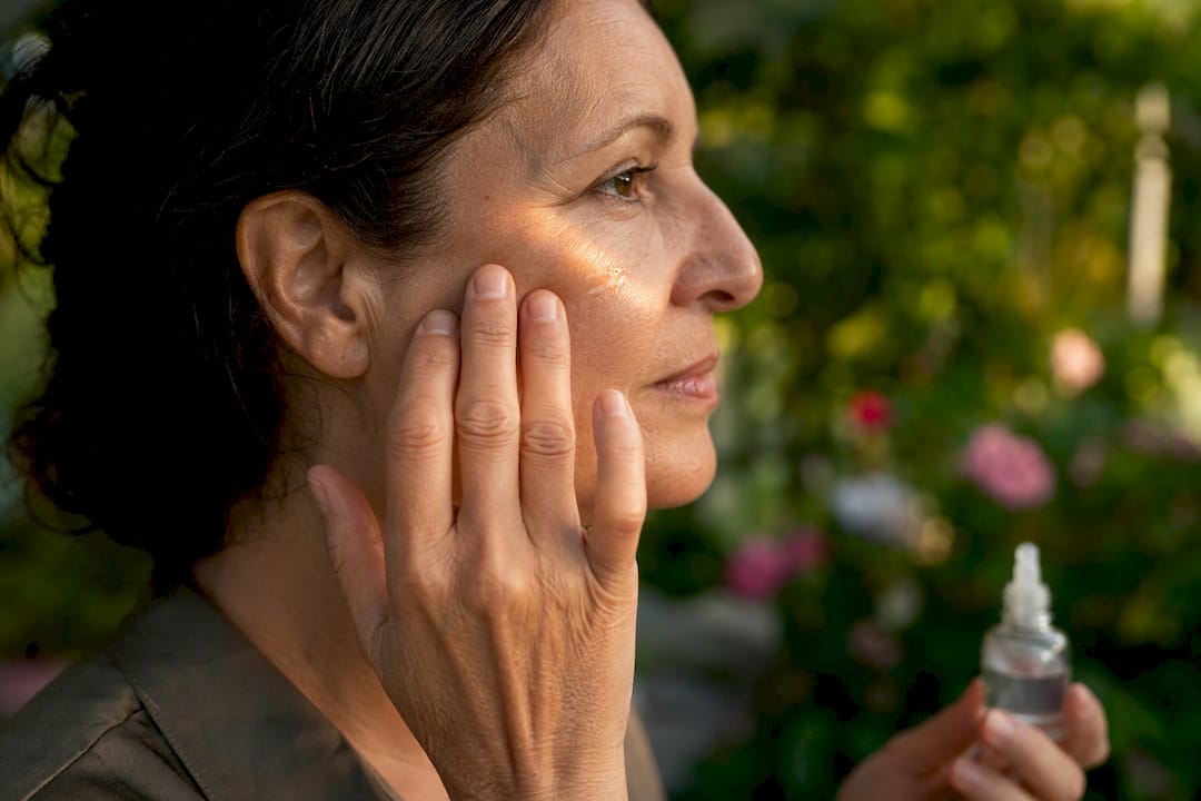 Hand applying peptide serum on cheek