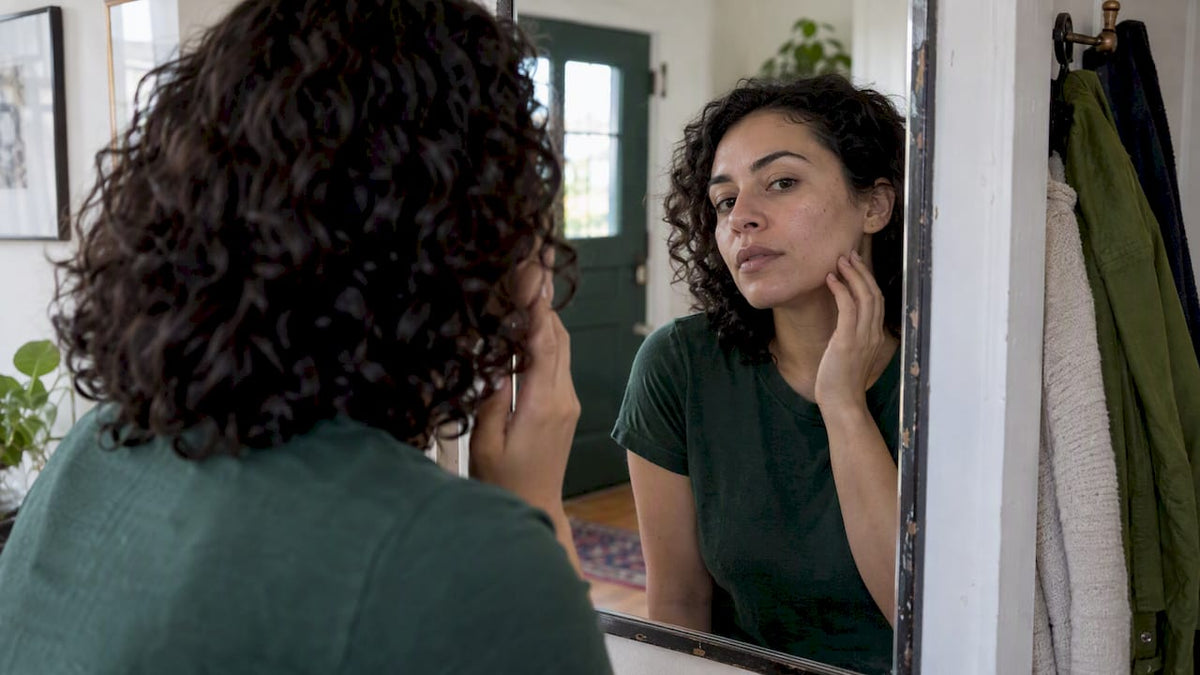 Woman examining her cheek in a mirror